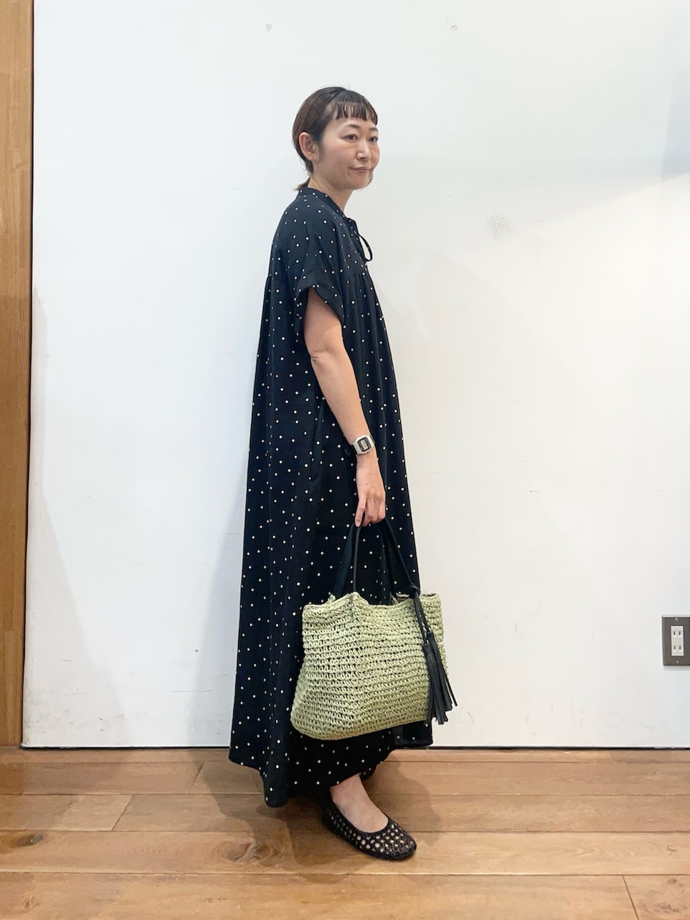 ブラック系のワンピース、グリーン系のかごバッグ、ブラック系のサンダルを着用したレディースの夏コーディネートの3枚目の写真
