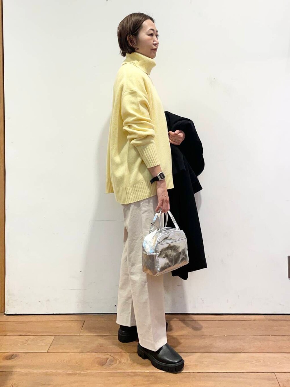 ブラック系のその他アウター、イエロー系のニット/セーター、ブラック系のブーツを着用したレディースの冬コーディネートの7枚目の写真