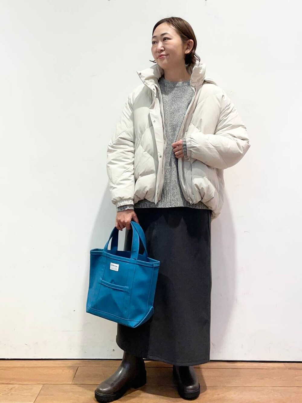 ホワイト系のダウンジャケット/コート、グレー系のニット/セーター、ブラウン系のブーツを着用したレディースの冬コーディネートの2枚目の写真