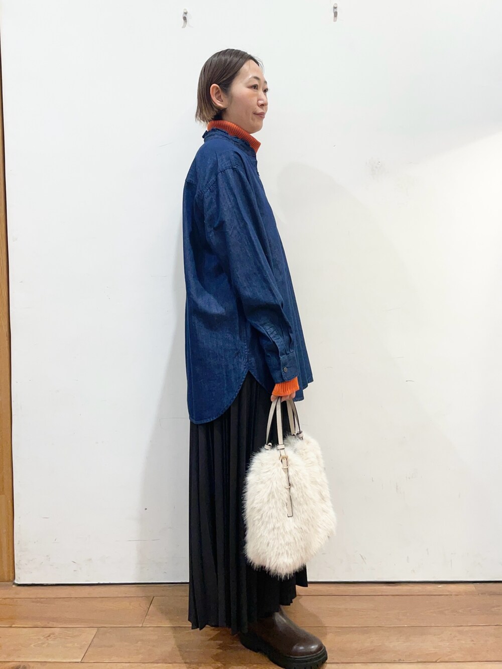 ブルー系のシャツ/ブラウス、オレンジ系のニット/セーター、ブラック系のスカートを着用したレディースの冬コーディネートの3枚目の写真