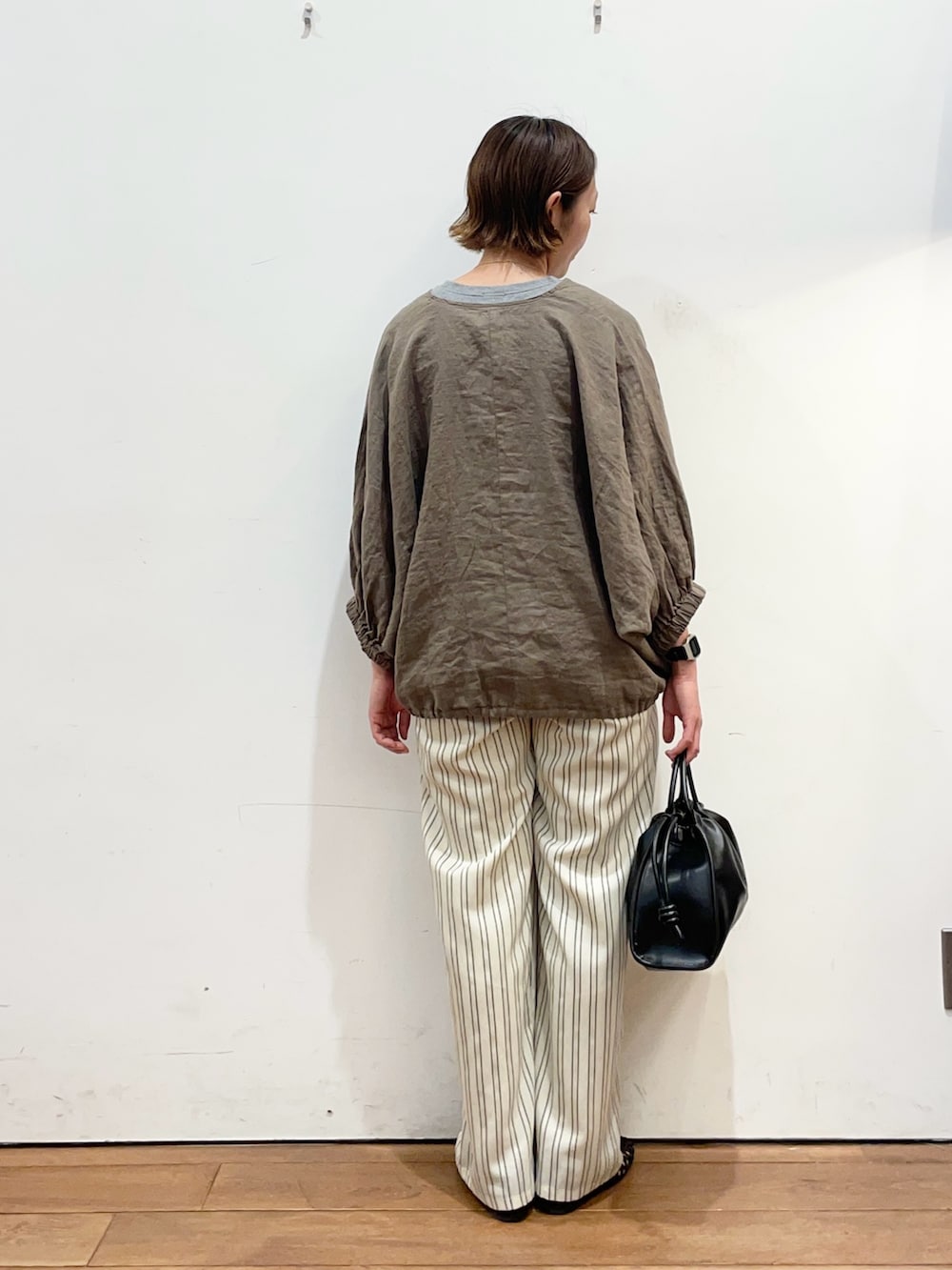 ブラウン系のシャツ/ブラウス、ベージュ系のその他パンツ、ブラック系のトートバッグを着用したレディースの春コーディネートの4枚目の写真