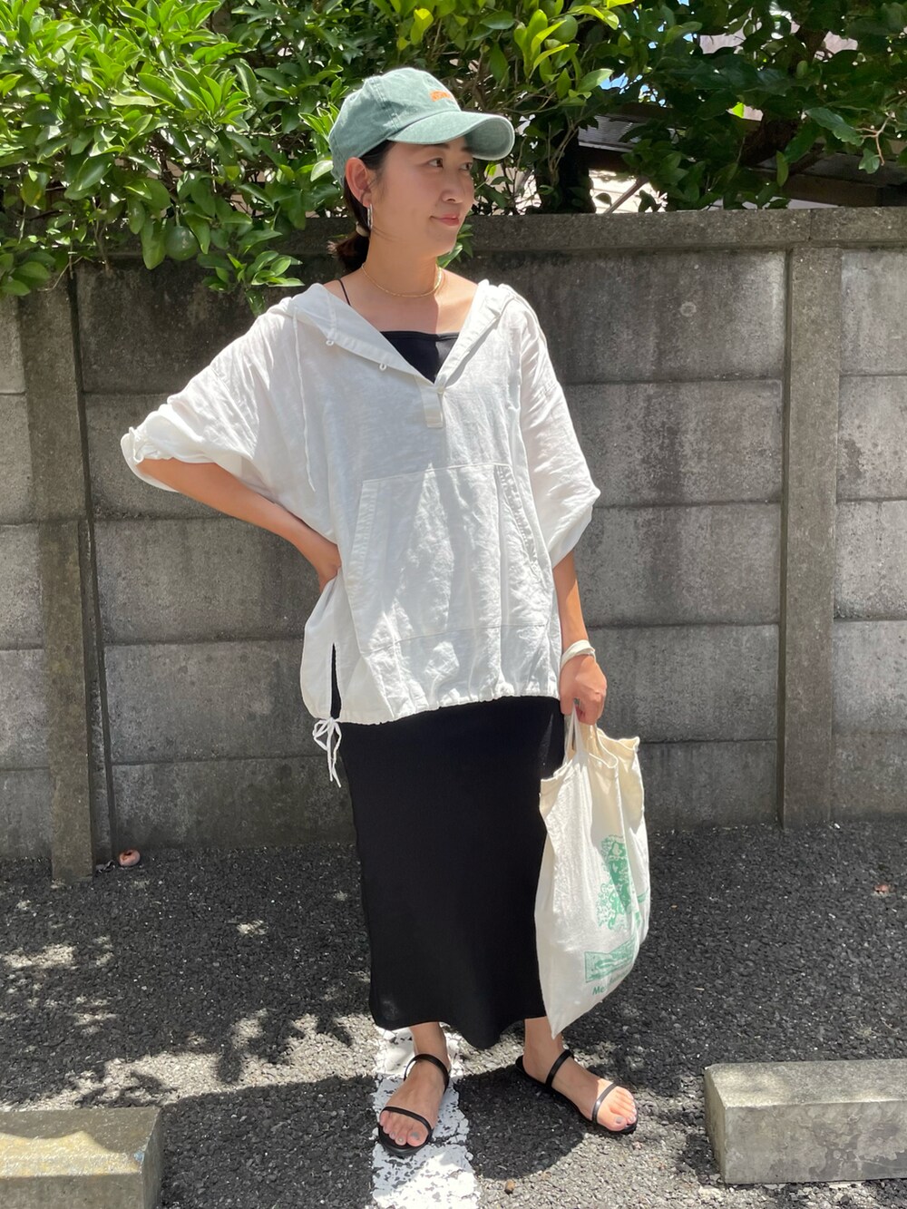 ブラック系のサンダル、ホワイト系のパーカー、グリーン系のキャップを着用したレディースの夏コーディネートの2枚目の写真