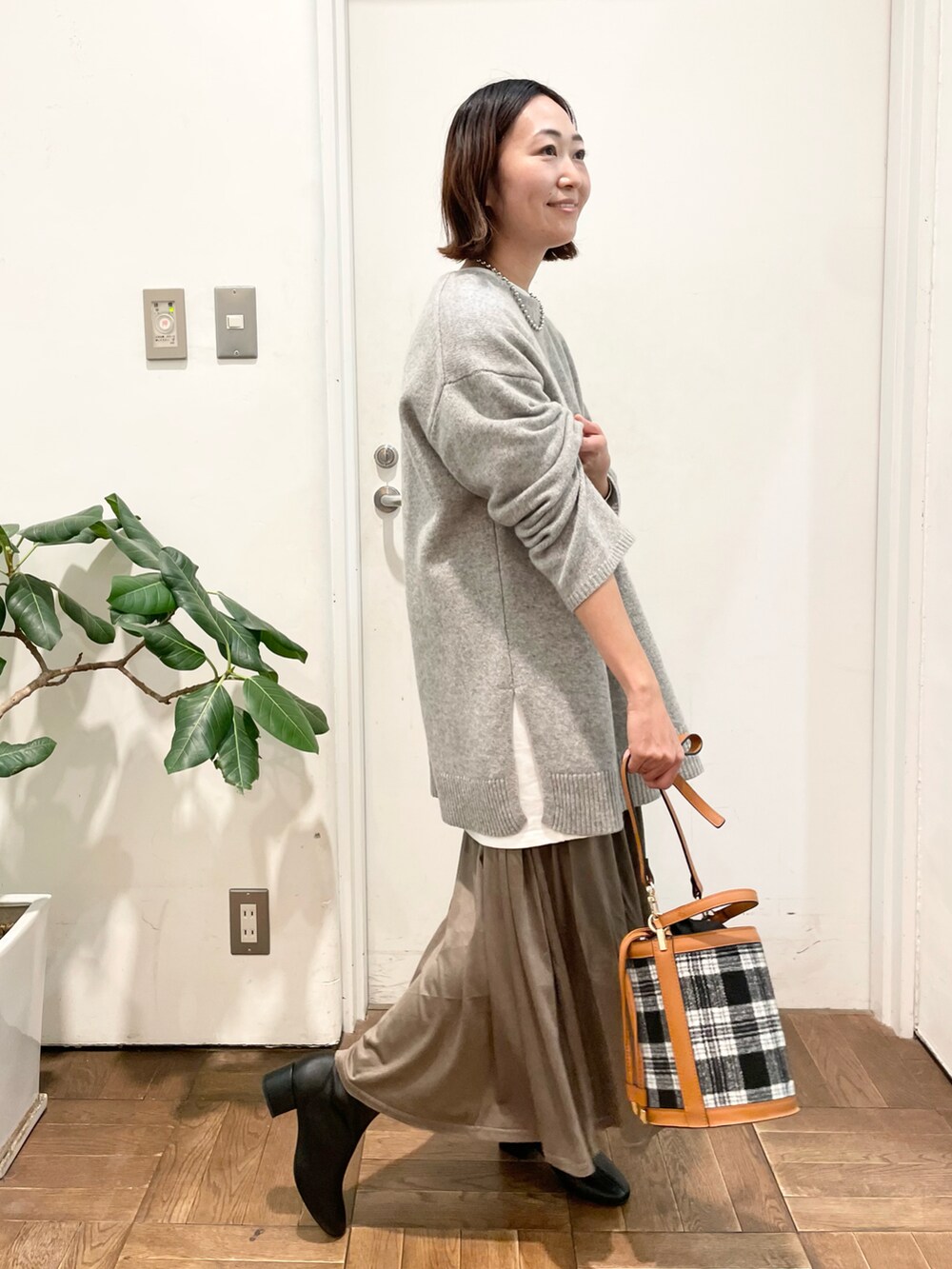 グレー系のニット/セーター、ブラウン系のスカート、ブラック系のブーツを着用したレディースの冬コーディネートの4枚目の写真