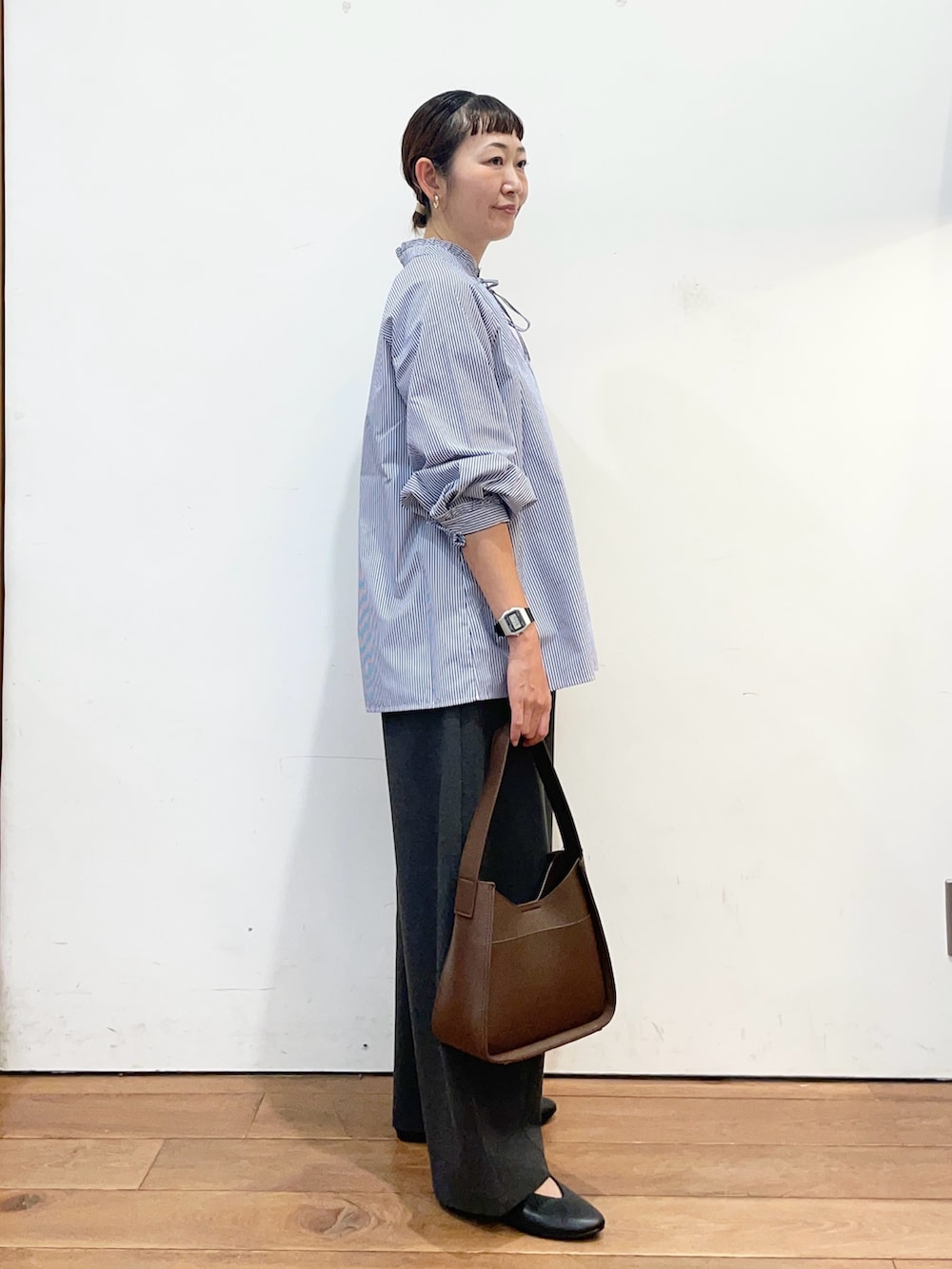 ブルー系のシャツ/ブラウス、グレー系のその他パンツ、ブラウン系のハンドバッグを着用したレディースの秋コーディネートの3枚目の写真