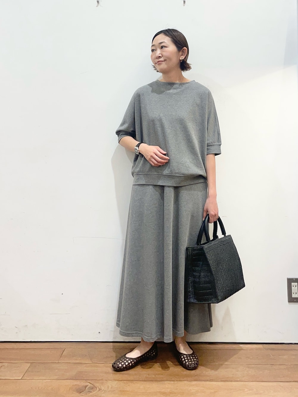 グレー系のTシャツ/カットソー、ブラウン系のサンダル、ブラック系のハンドバッグを着用したレディースの春コーディネートの2枚目の写真
