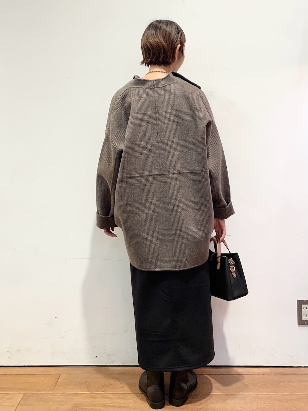 ブラック系のブーツ、ブラック系のハンドバッグ、その他のその他アウターを着用したレディースの秋コーディネートの4枚目の写真