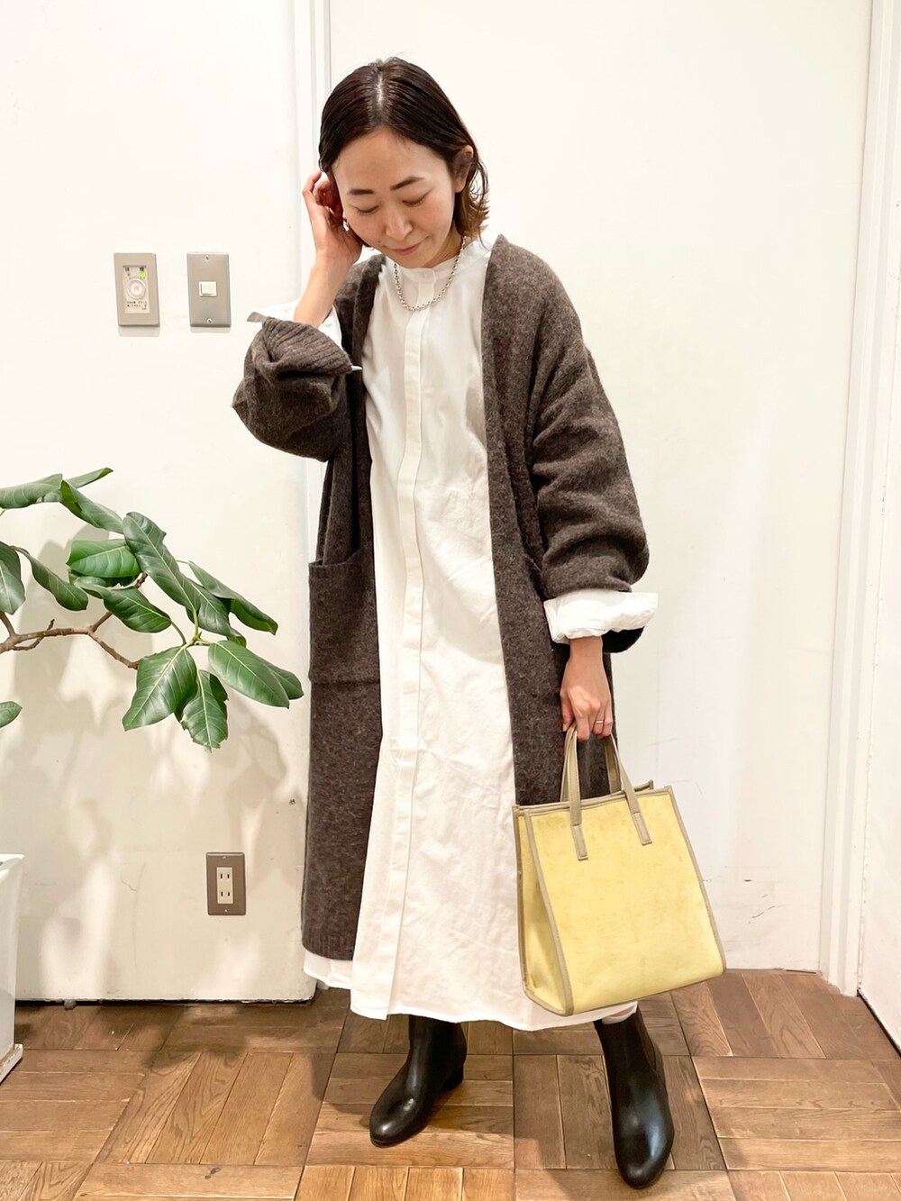 ブラウン系のカーディガン/ボレロ、ホワイト系のワンピース、イエロー系のショルダーバッグを着用したレディースの冬コーディネートの3枚目の写真