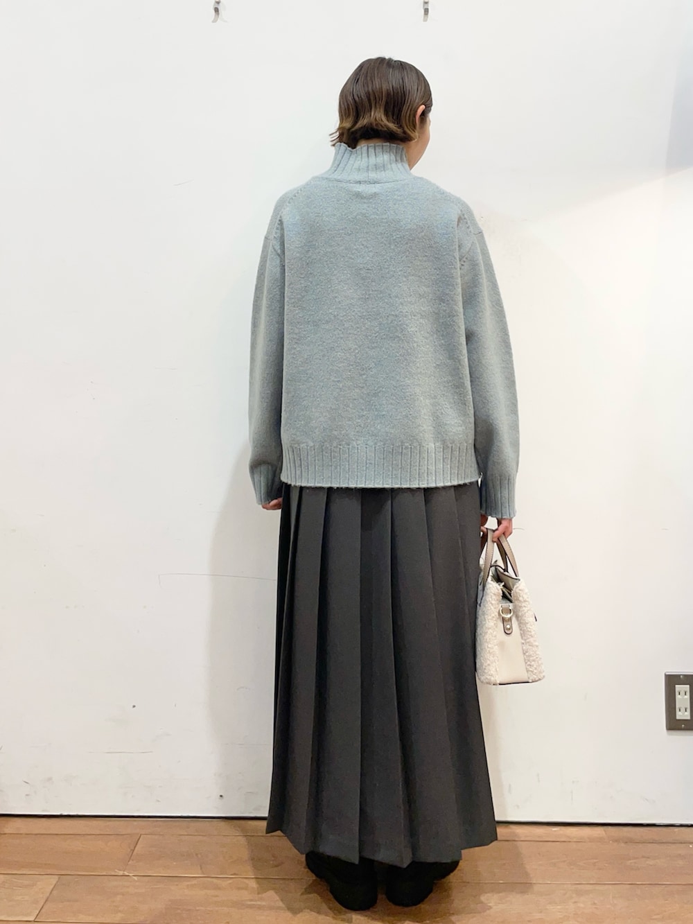 グリーン系のニット/セーター、グレー系のスカート、ブラック系のブーツを着用したレディースの冬コーディネートの4枚目の写真