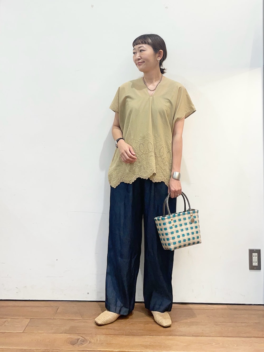 ベージュ系のシャツ/ブラウス、ベージュ系のバレエシューズ、グリーン系のショルダーバッグを着用したレディースの夏コーディネートの2枚目の写真