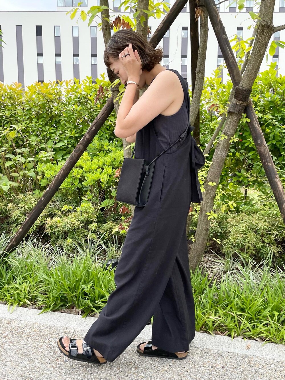 ブラック系のサロペット/オーバーオール、ブラック系のショルダーバッグ、ブラック系のサンダルを着用したレディースの夏コーディネートの2枚目の写真