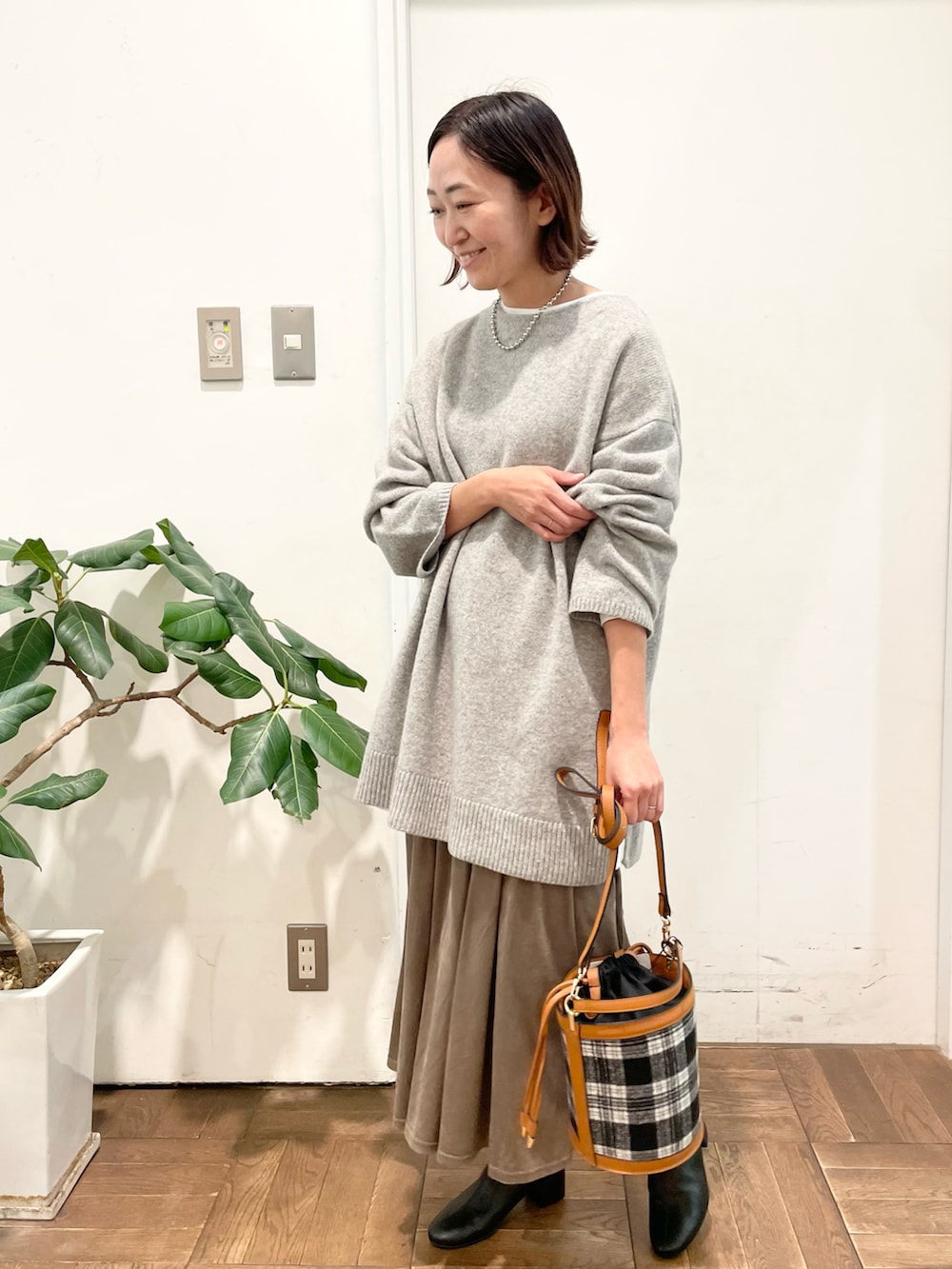 グレー系のニット/セーター、ブラウン系のスカート、ブラック系のブーツを着用したレディースの冬コーディネートの2枚目の写真