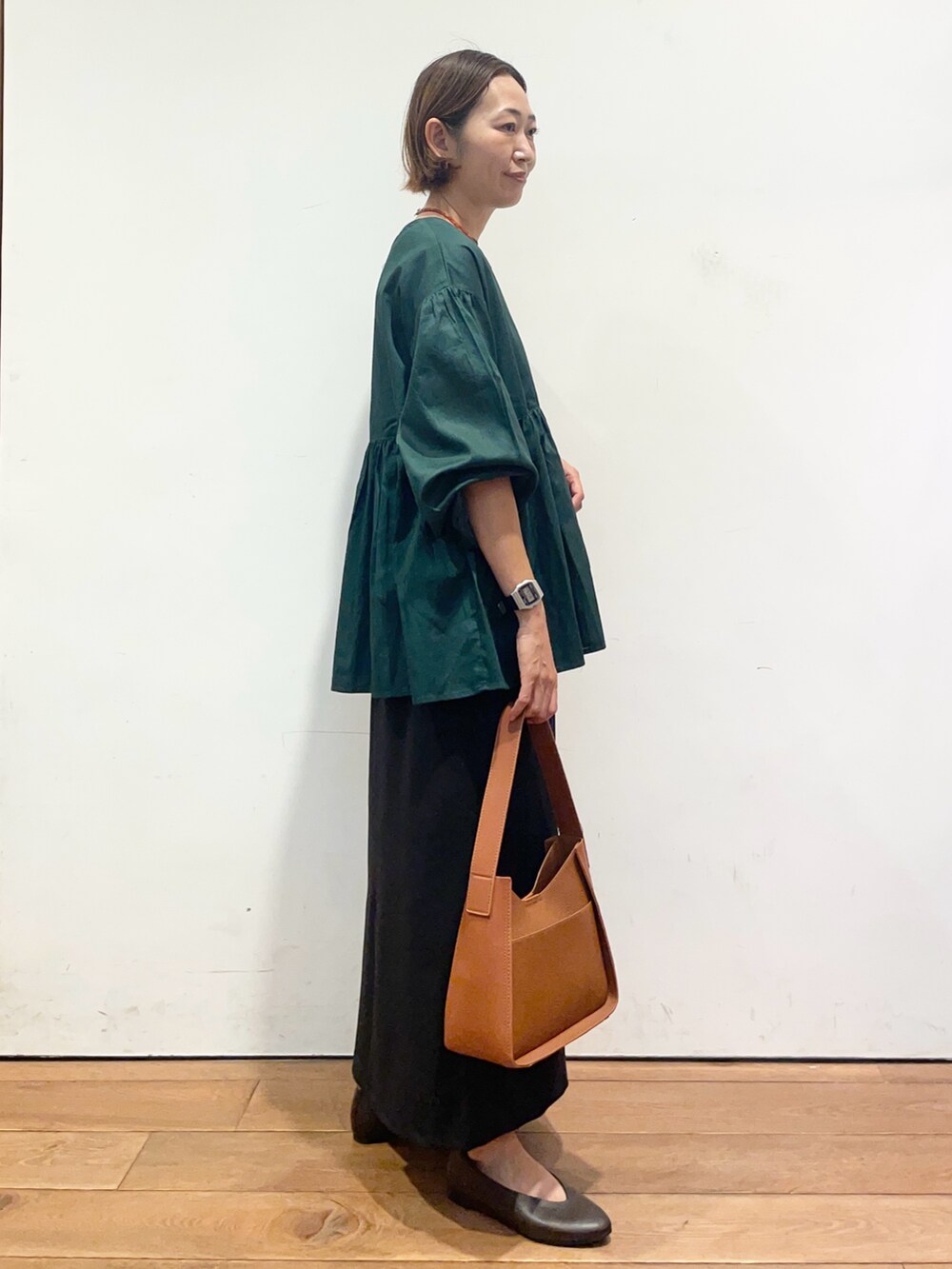 ブラウン系のパンプス、ブラウン系のハンドバッグ、グリーン系のシャツ/ブラウスを着用したレディースの秋コーディネートの4枚目の写真
