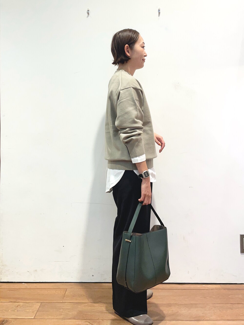 ベージュ系のニット/セーター、ホワイト系のTシャツ/カットソー、グリーン系のハンドバッグを着用したレディースの秋コーディネートの3枚目の写真