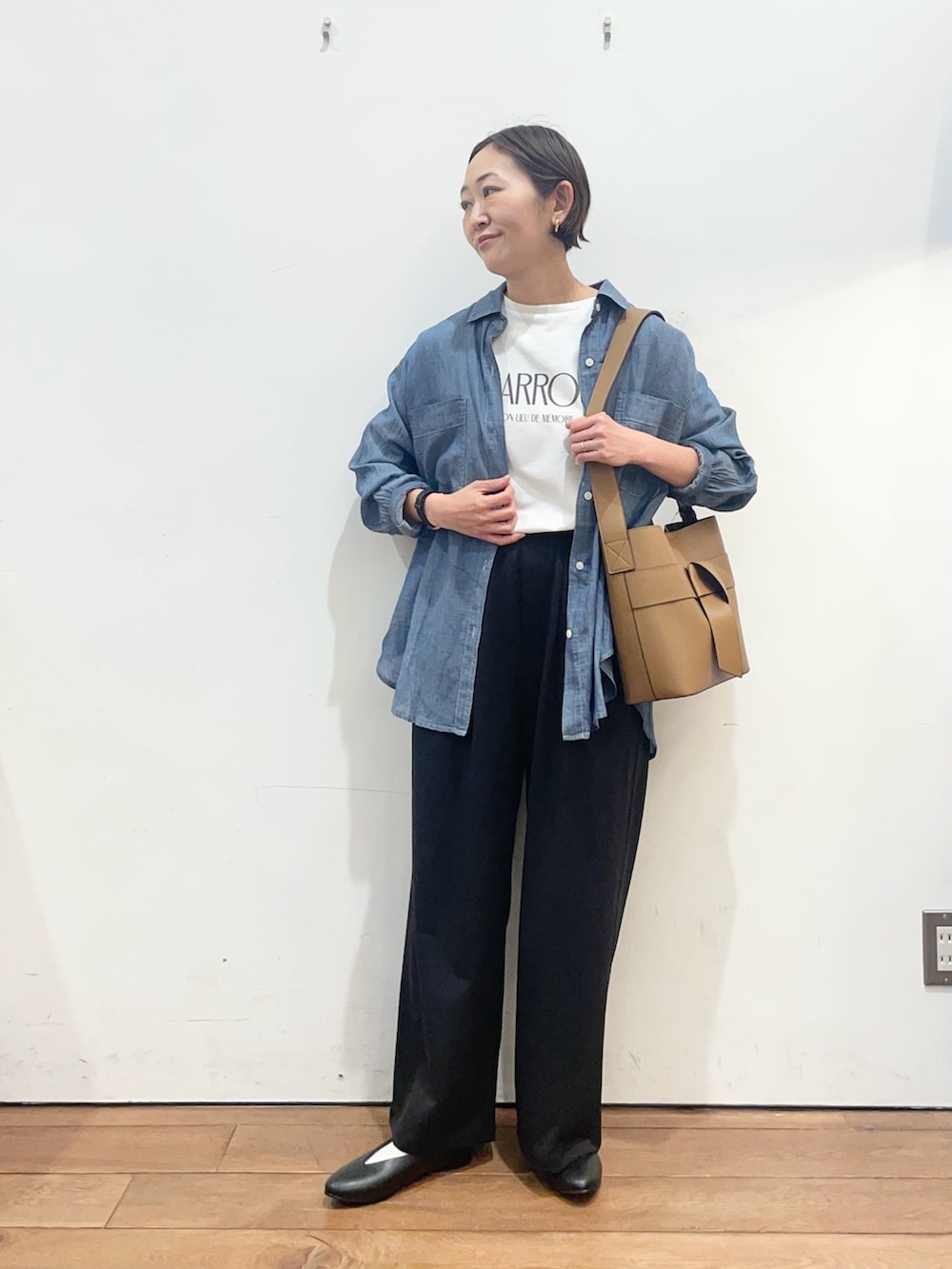 ブルー系のシャツ/ブラウス、ブラック系のパンプス、イエロー系のショルダーバッグを着用したレディースの春コーディネートの2枚目の写真