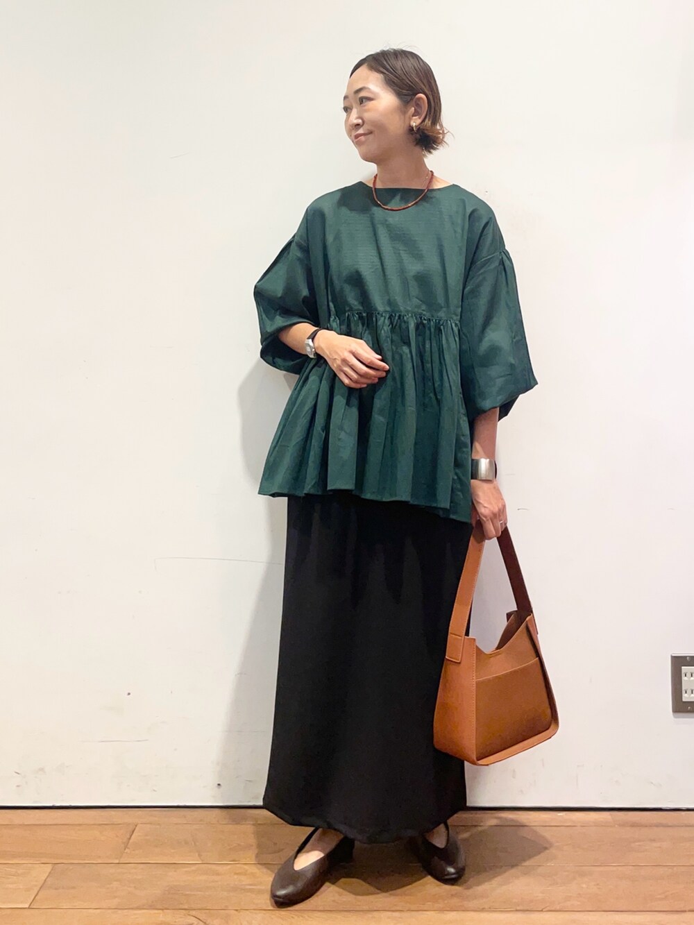 ブラウン系のパンプス、ブラウン系のハンドバッグ、グリーン系のシャツ/ブラウスを着用したレディースの秋コーディネートの2枚目の写真