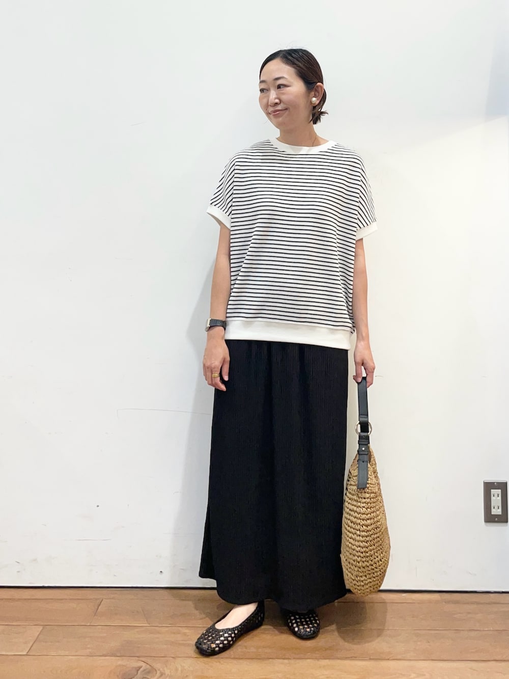 ブラック系のサンダル、イエロー系のトートバッグ、ホワイト系のTシャツ/カットソーを着用したレディースの春コーディネートの2枚目の写真