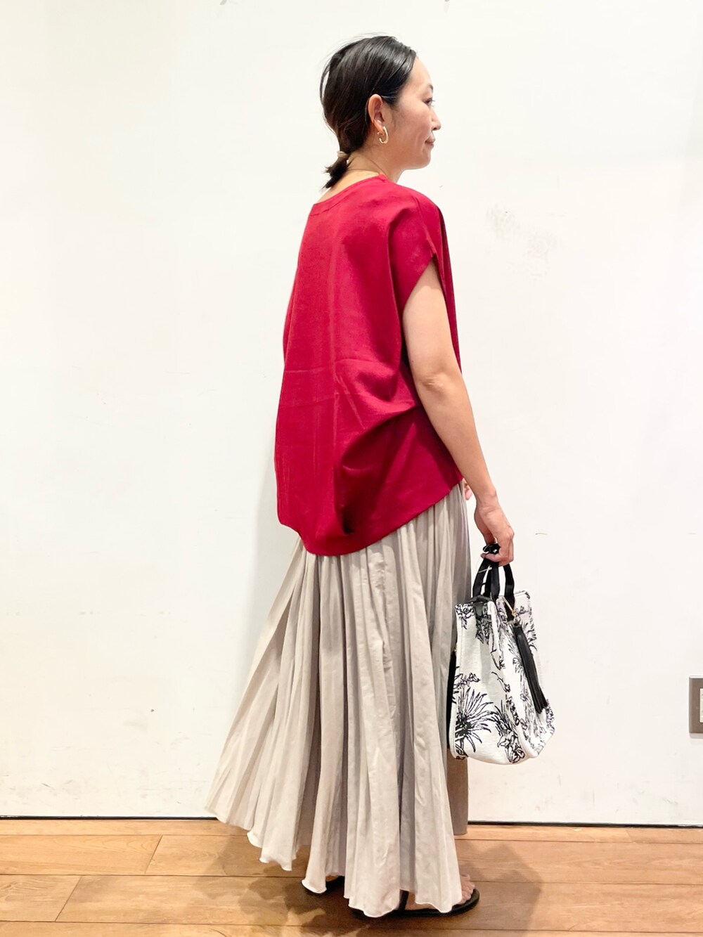 レッド系のTシャツ/カットソー、ベージュ系のスカート、ブラック系のサンダルを着用したレディースの夏コーディネートの4枚目の写真