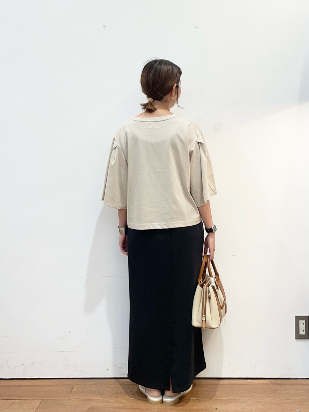 ベージュ系のTシャツ/カットソー、ブラック系のスカート、ホワイト系のハンドバッグを着用したレディースの夏コーディネートの4枚目の写真