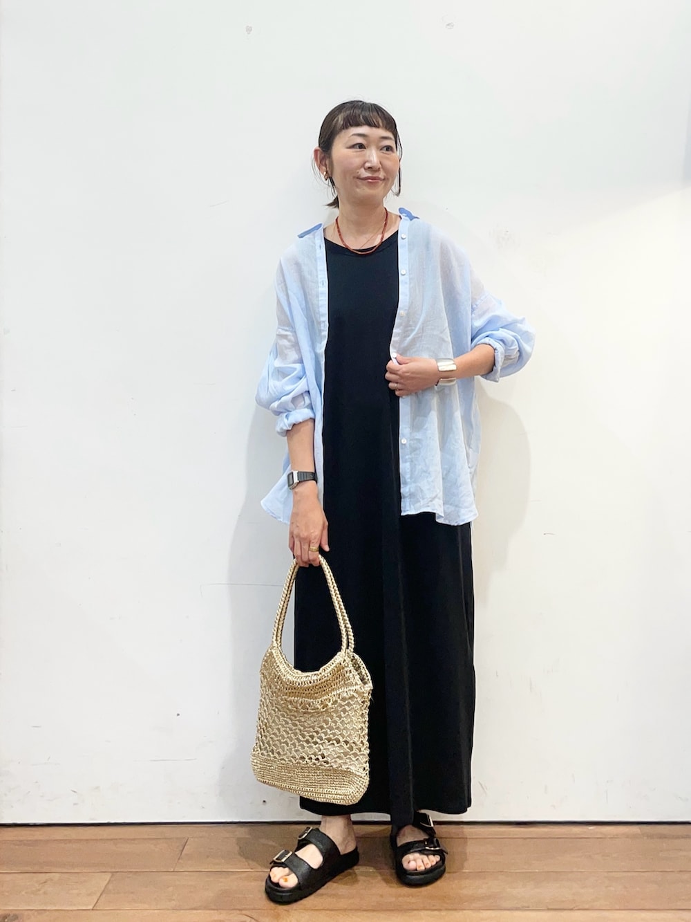 ブルー系のシャツ/ブラウス、ブラック系のワンピース、ゴールド系のトートバッグを着用したレディースの夏コーディネートの3枚目の写真
