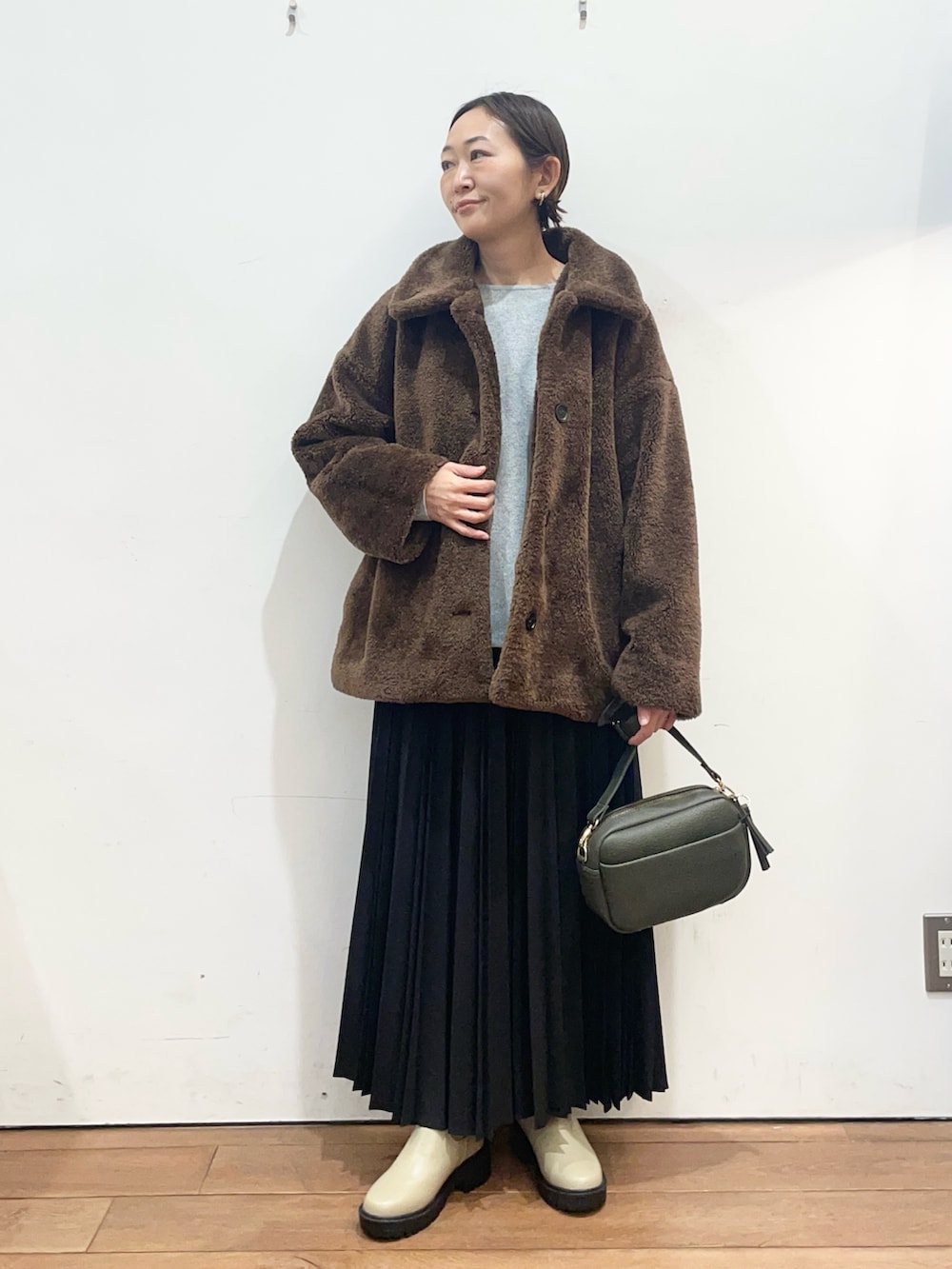 ブラウン系のその他アウター、グレー系のニット/セーター、グリーン系のショルダーバッグを着用したレディースの冬コーディネートの2枚目の写真