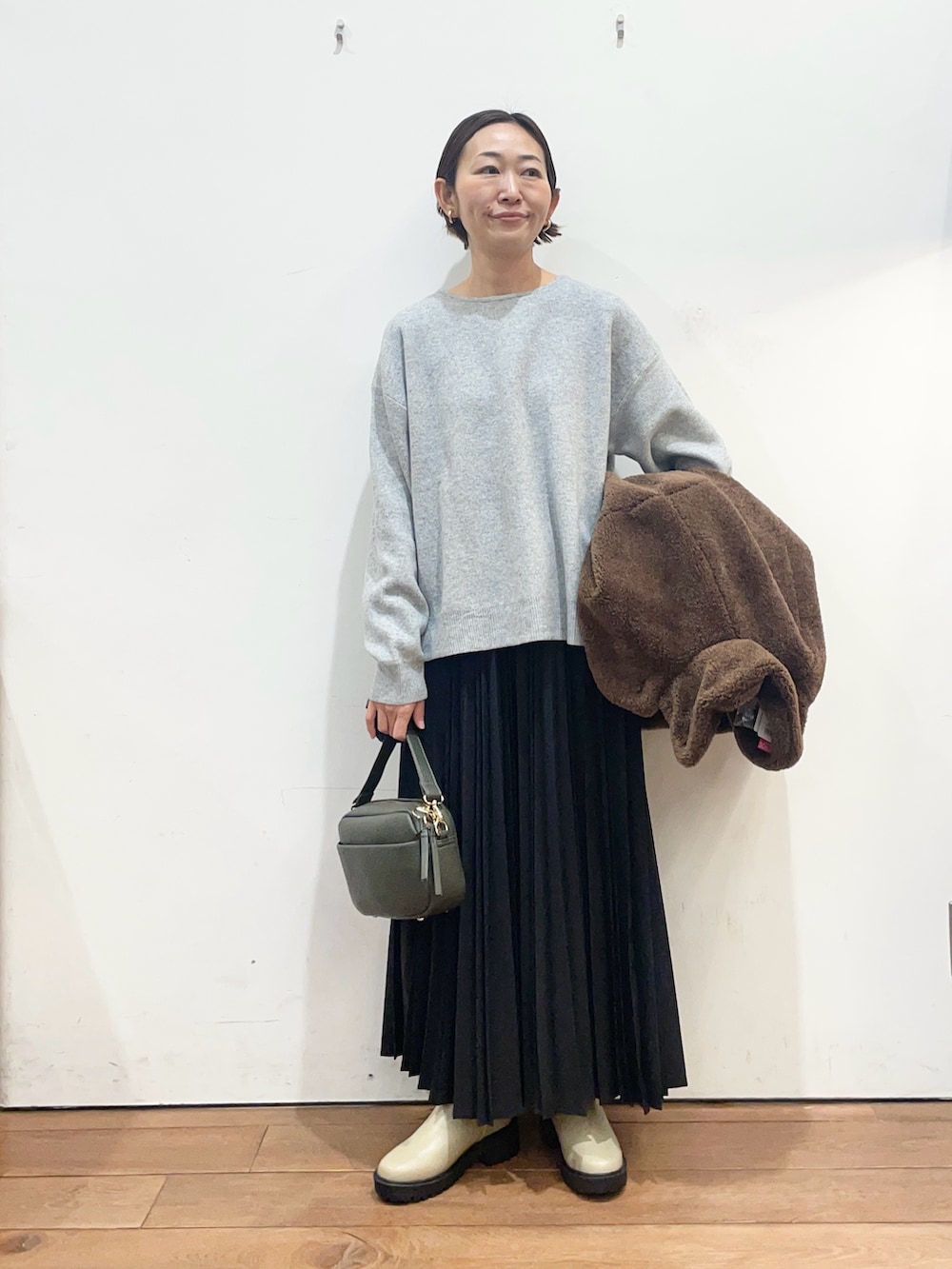 ブラウン系のその他アウター、グレー系のニット/セーター、グリーン系のショルダーバッグを着用したレディースの冬コーディネートの6枚目の写真