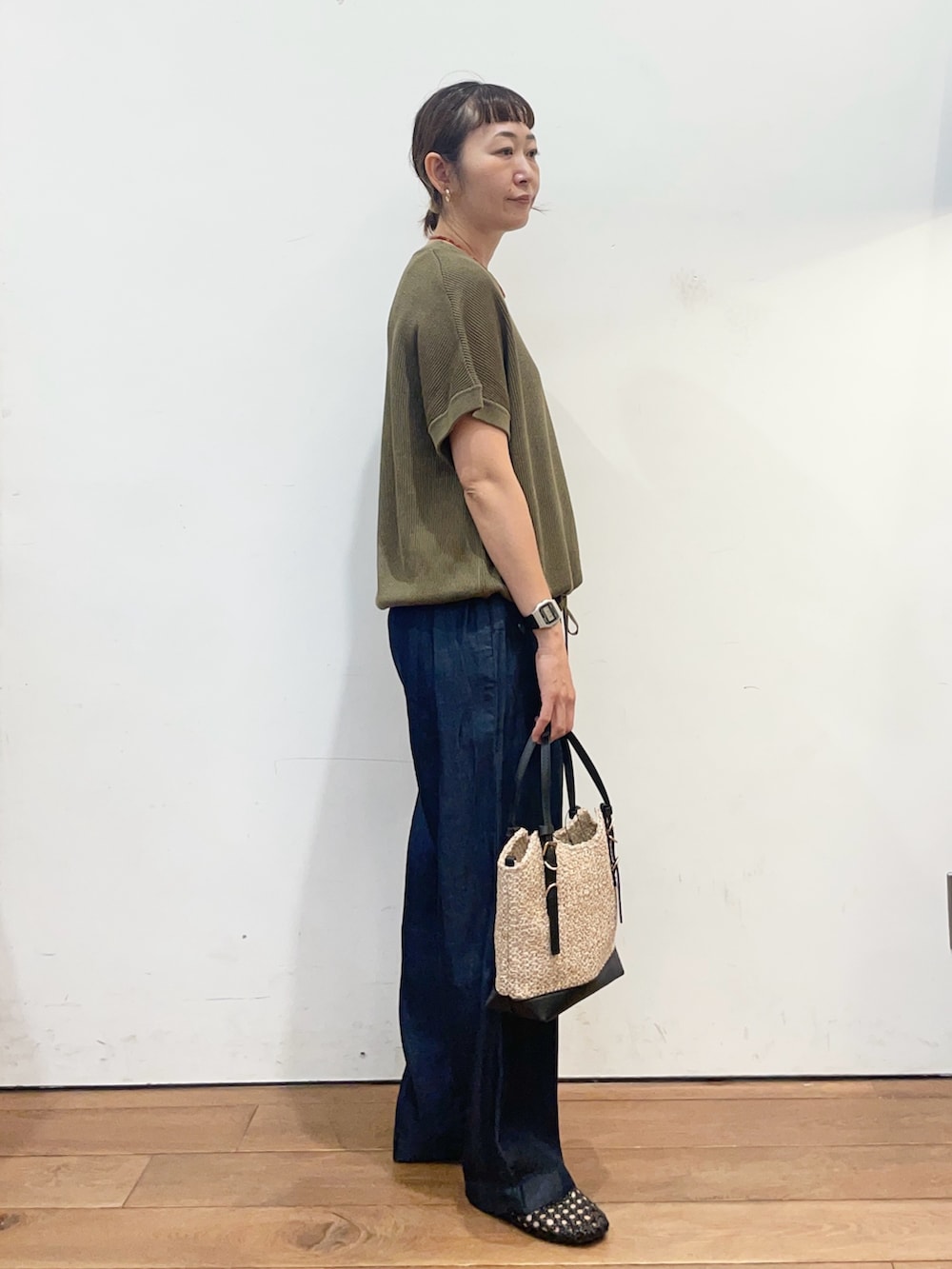 グリーン系のニット/セーター、ブルー系のデニムパンツ、ブラック系のサンダルを着用したレディースの夏コーディネートの3枚目の写真