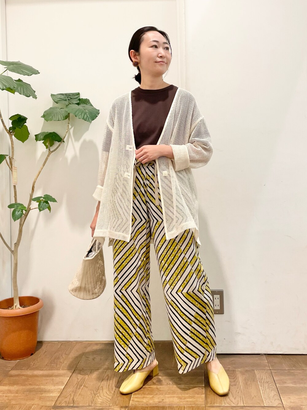 ブラウン系のTシャツ/カットソー、ベージュ系のカーディガン/ボレロ、ホワイト系のハンドバッグを着用したレディースの春コーディネートの2枚目の写真