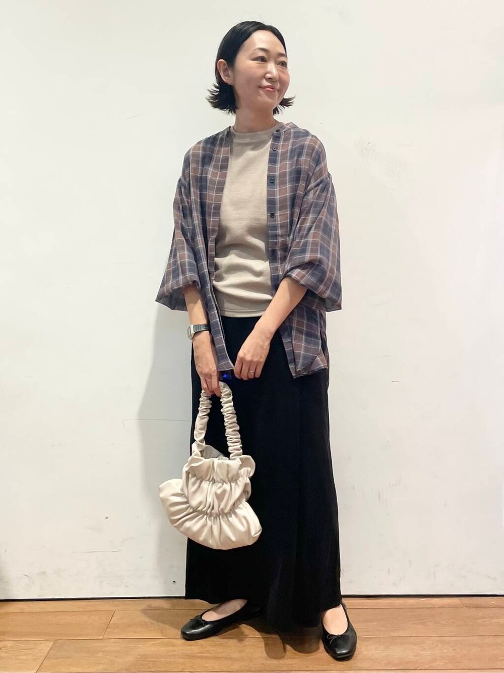 ホワイト系のハンドバッグ、ブラック系のワンピース、ブラック系のスカートを着用したレディースの秋コーディネートの2枚目の写真