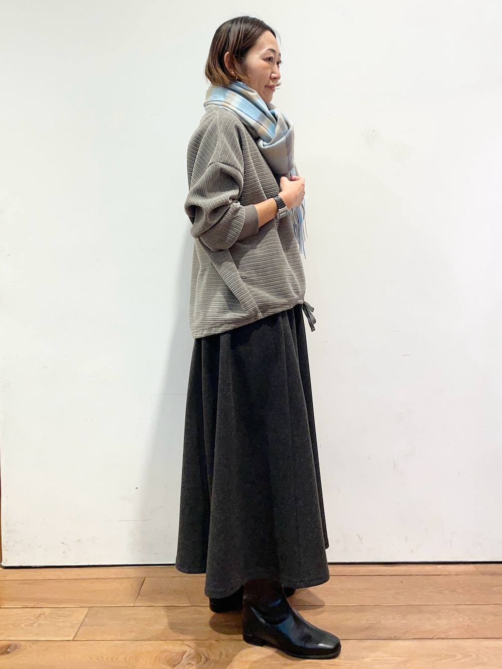 グレー系のスカート、ブラック系のブーツ、グレー系のTシャツ/カットソーを着用したレディースの冬コーディネートの4枚目の写真