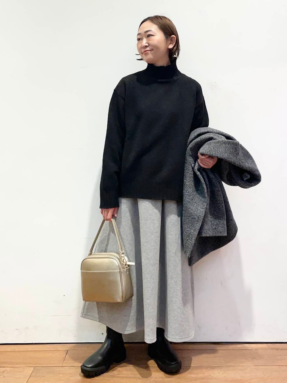 ゴールド系のショルダーバッグ、ブラック系のブーツ、グレー系のその他アウターを着用したレディースの冬コーディネートの5枚目の写真