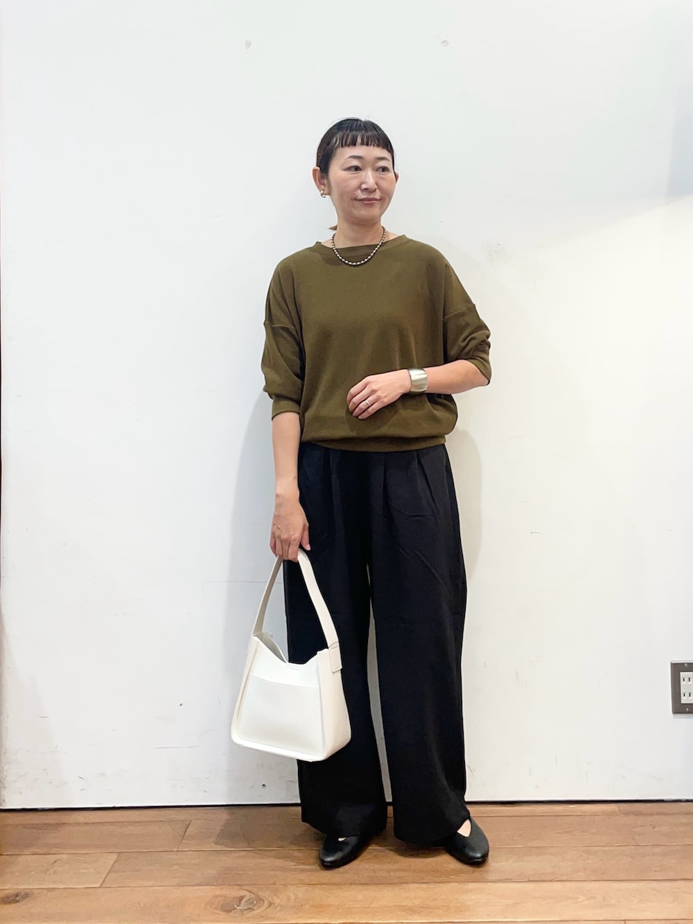 ブラウン系のTシャツ/カットソー、ブラック系のその他パンツ、ホワイト系のハンドバッグを着用したレディースの秋コーディネートの2枚目の写真