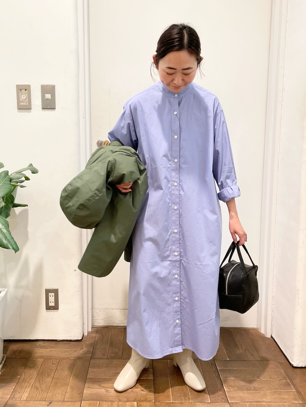 グリーン系のマウンテンパーカー、ブルー系のワンピース、ホワイト系のブーツを着用したレディースの冬コーディネートの2枚目の写真