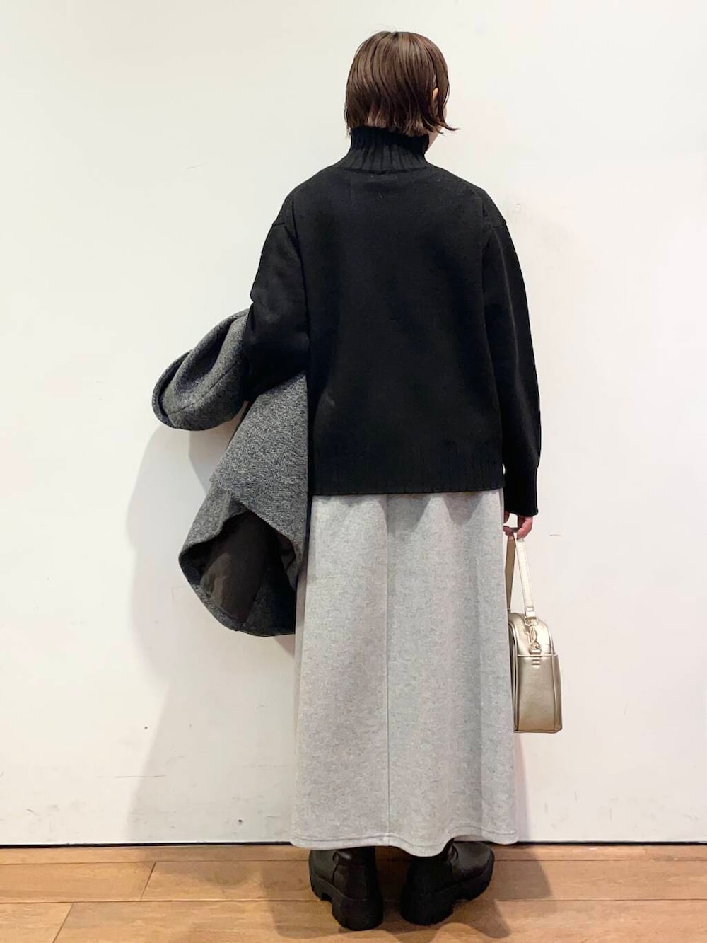 ゴールド系のショルダーバッグ、ブラック系のブーツ、グレー系のその他アウターを着用したレディースの冬コーディネートの6枚目の写真