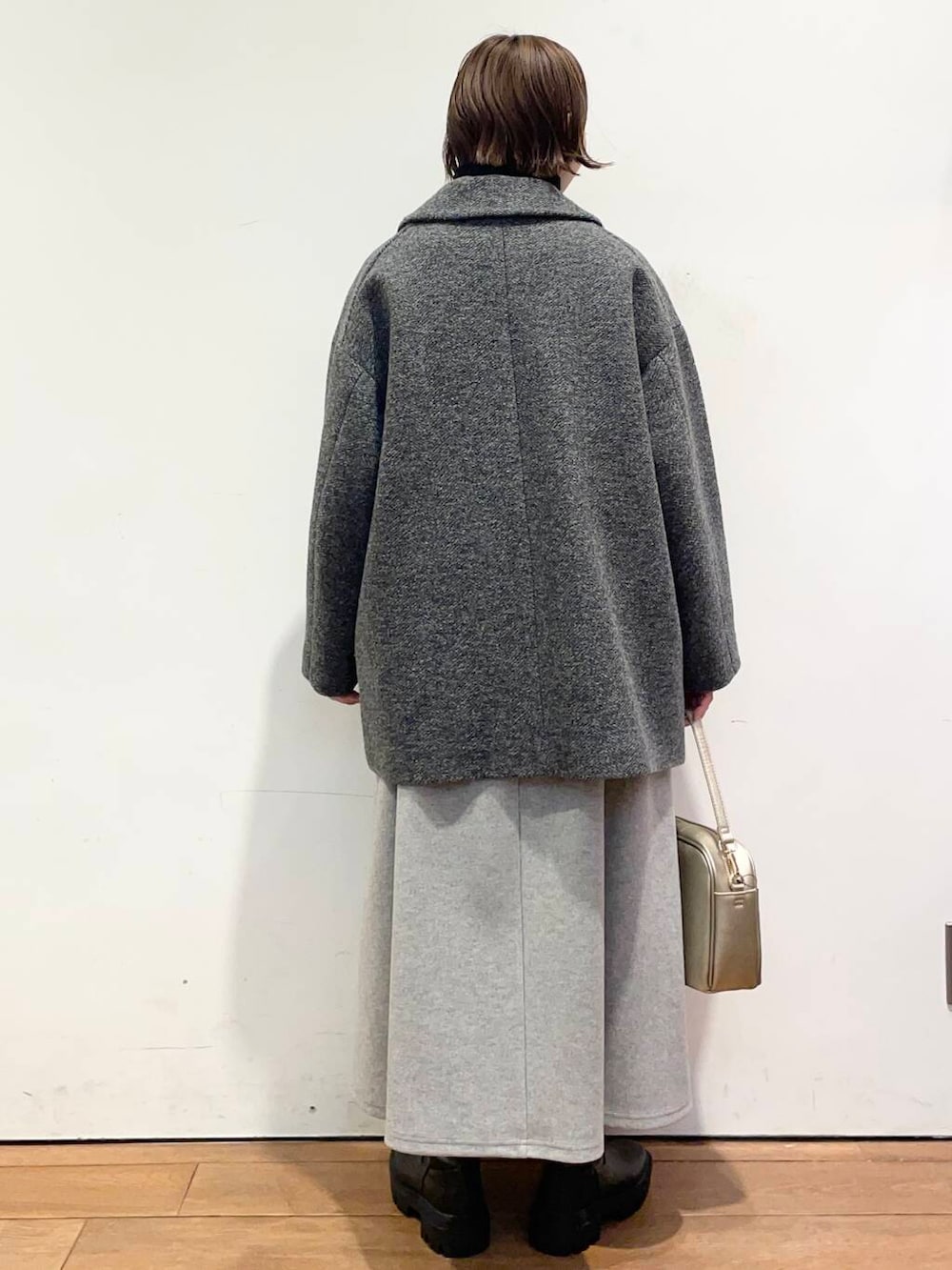 ゴールド系のショルダーバッグ、ブラック系のブーツ、グレー系のその他アウターを着用したレディースの冬コーディネートの4枚目の写真