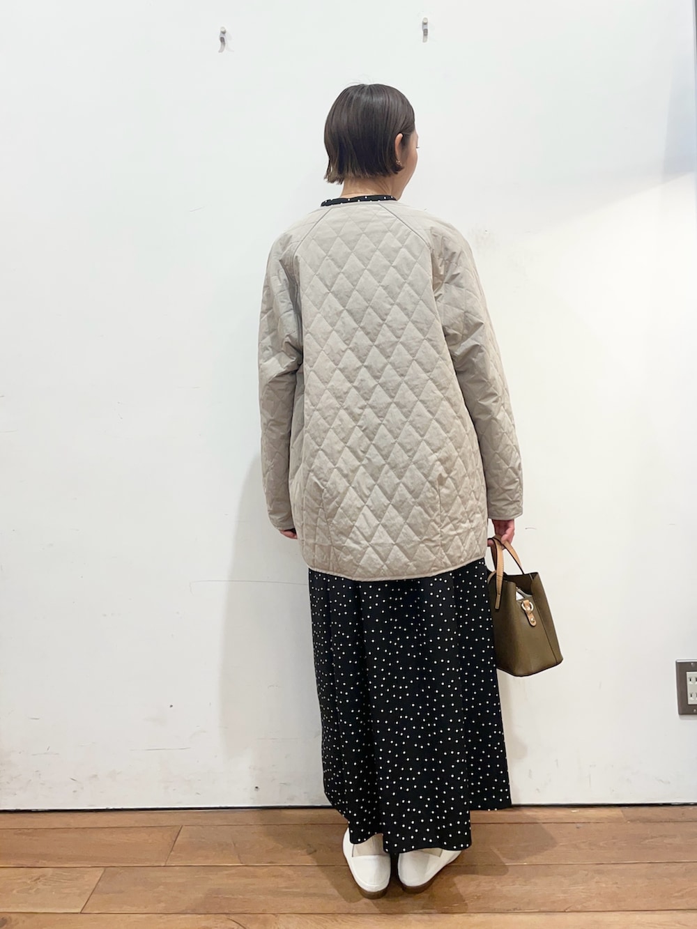 グレー系のダウンジャケット/コート、ホワイト系のその他シューズ、ブラック系のワンピースを着用したレディースの春コーディネートの4枚目の写真