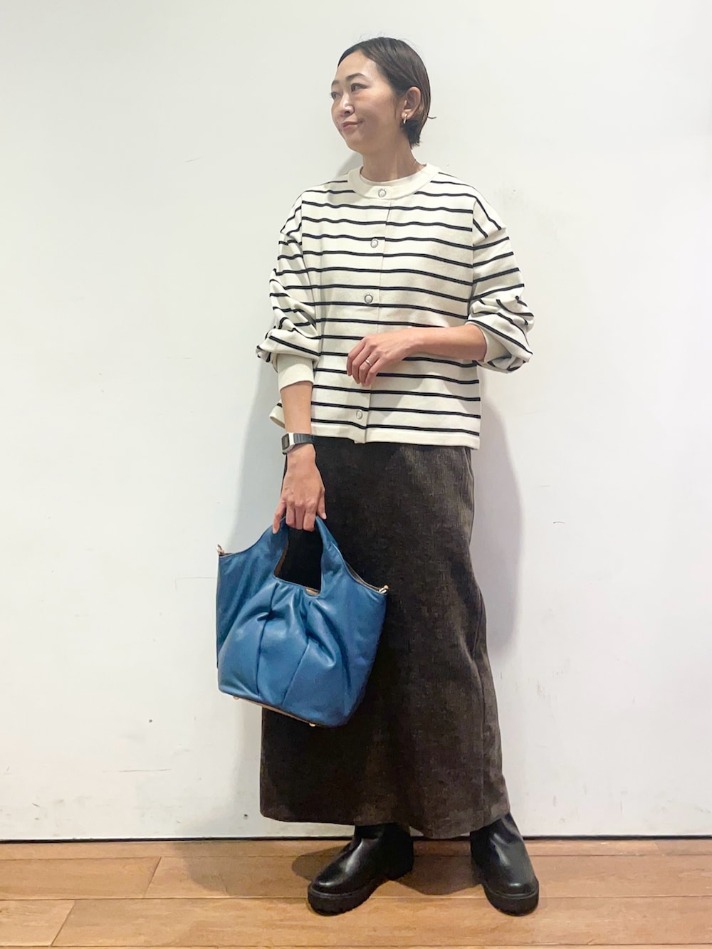 ホワイト系のカーディガン/ボレロ、ブラウン系のスカート、ブラック系のブーツを着用したレディースの秋コーディネートの3枚目の写真