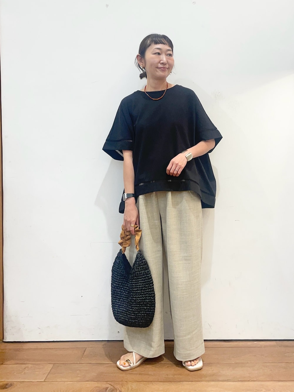 ブラック系のTシャツ/カットソー、ベージュ系のその他パンツ、オレンジ系のかごバッグを着用したレディースの夏コーディネートの2枚目の写真