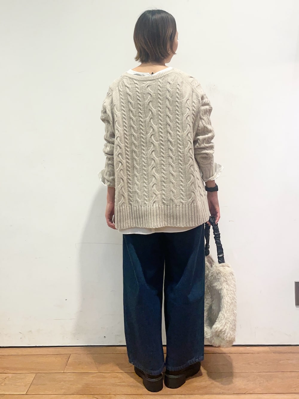 ベージュ系のニット/セーター、ホワイト系のシャツ/ブラウス、ブルー系のデニムパンツを着用したレディースの冬コーディネートの5枚目の写真