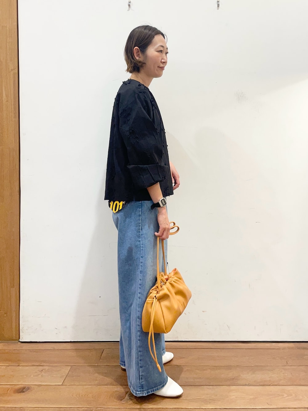 ブラック系のシャツ/ブラウス、ブルー系のデニムパンツ、オレンジ系のショルダーバッグを着用したレディースの冬コーディネートの4枚目の写真