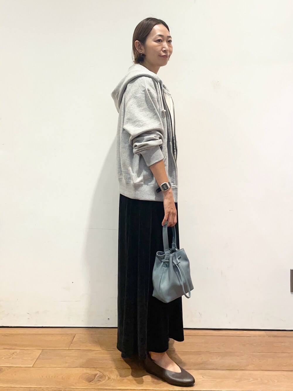 ブルー系のショルダーバッグ、ブラウン系のパンプス、ブラック系のワンピースを着用したレディースの秋コーディネートの4枚目の写真