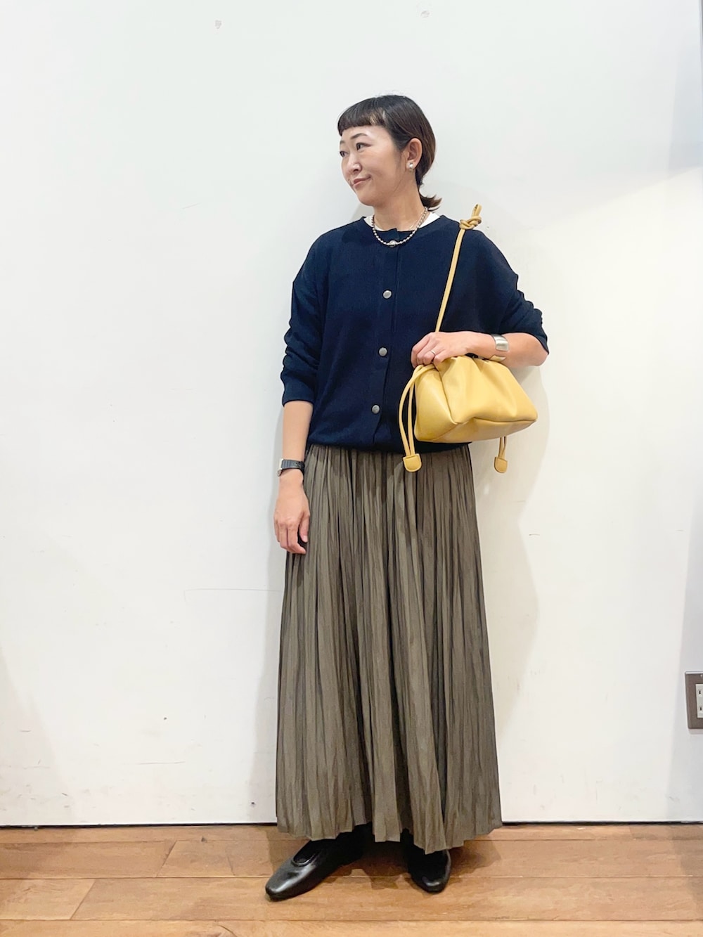 ブルー系のカーディガン/ボレロ、ベージュ系のスカート、イエロー系のショルダーバッグを着用したレディースの秋コーディネートの2枚目の写真