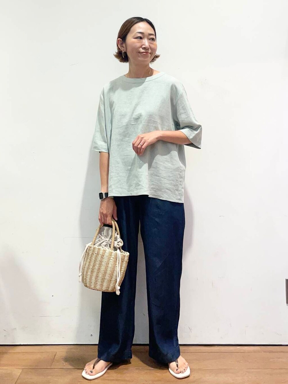 グレー系のハンドバッグ、ブラウン系のサンダル、ブルー系のデニムパンツを着用したレディースの夏コーディネートの3枚目の写真