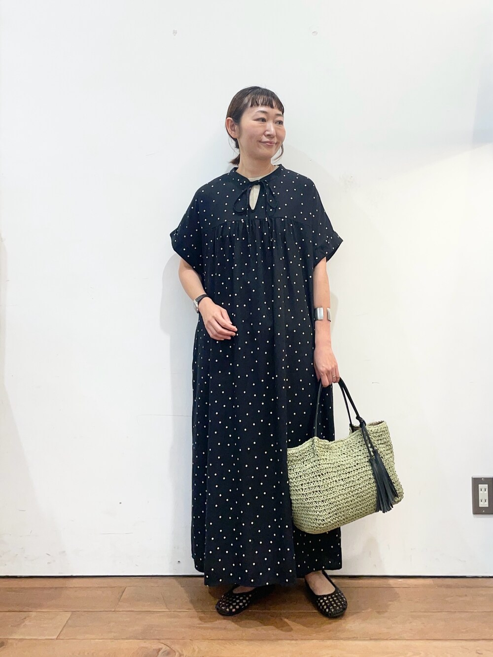 ブラック系のワンピース、グリーン系のかごバッグ、ブラック系のサンダルを着用したレディースの夏コーディネートの2枚目の写真