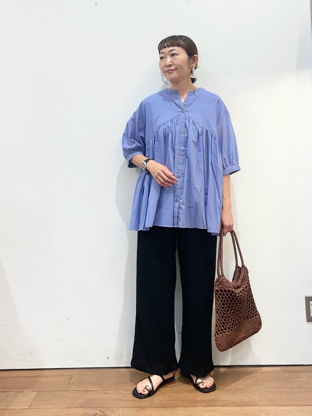 ブルー系のシャツ/ブラウス、ブラック系のその他パンツ、ブラウン系のトートバッグを着用したレディースの夏コーディネートの3枚目の写真