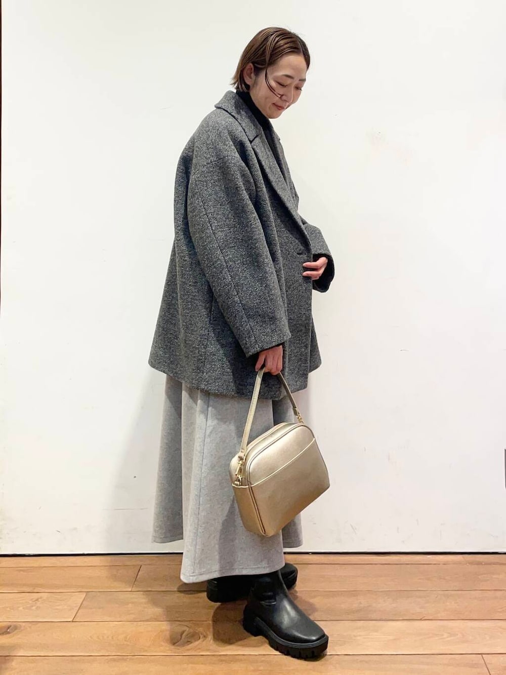 ゴールド系のショルダーバッグ、ブラック系のブーツ、グレー系のその他アウターを着用したレディースの冬コーディネートの3枚目の写真