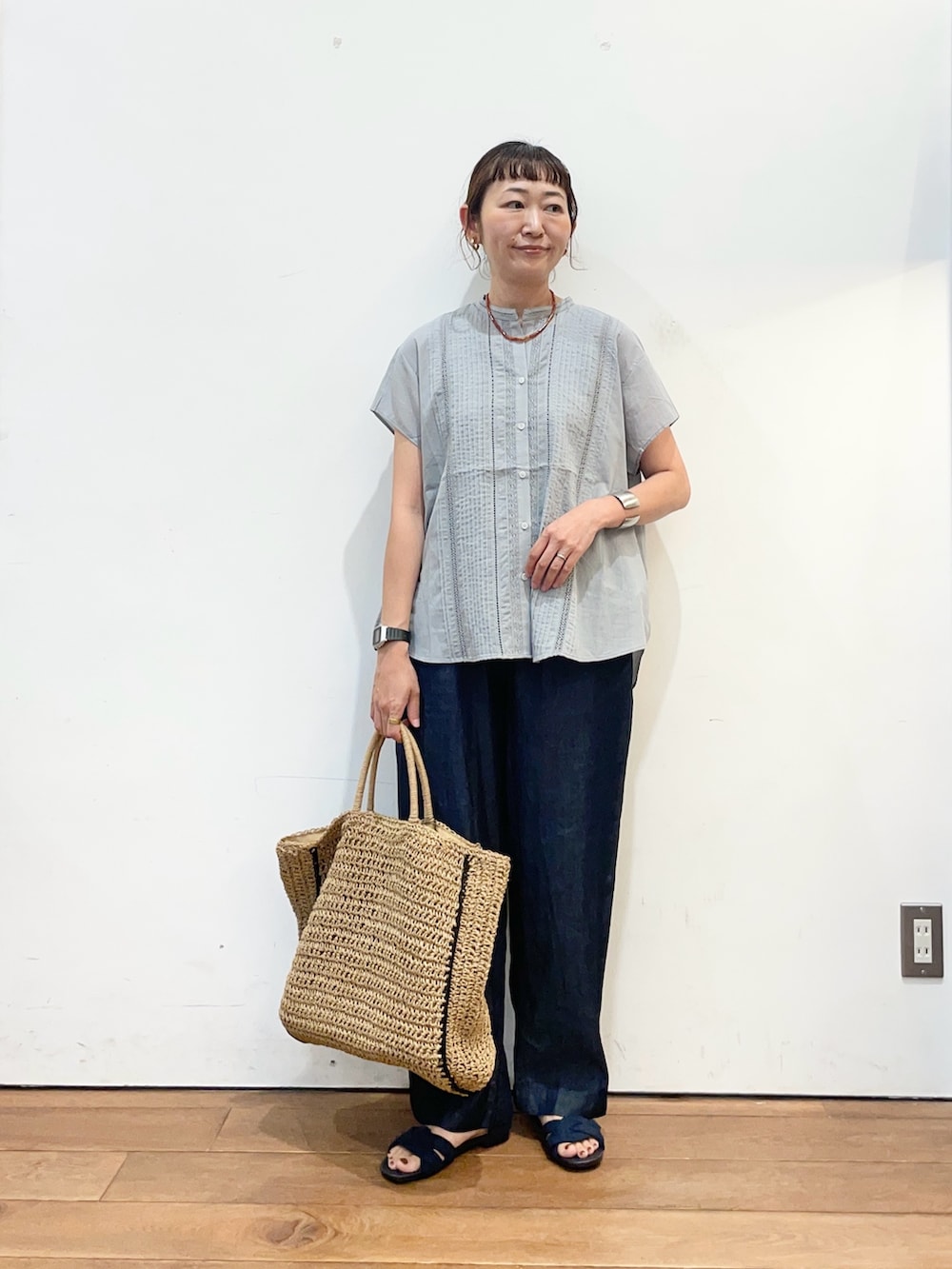 グレー系のシャツ/ブラウス、ブルー系のデニムパンツ、ベージュ系のトートバッグを着用したレディースの夏コーディネートの2枚目の写真