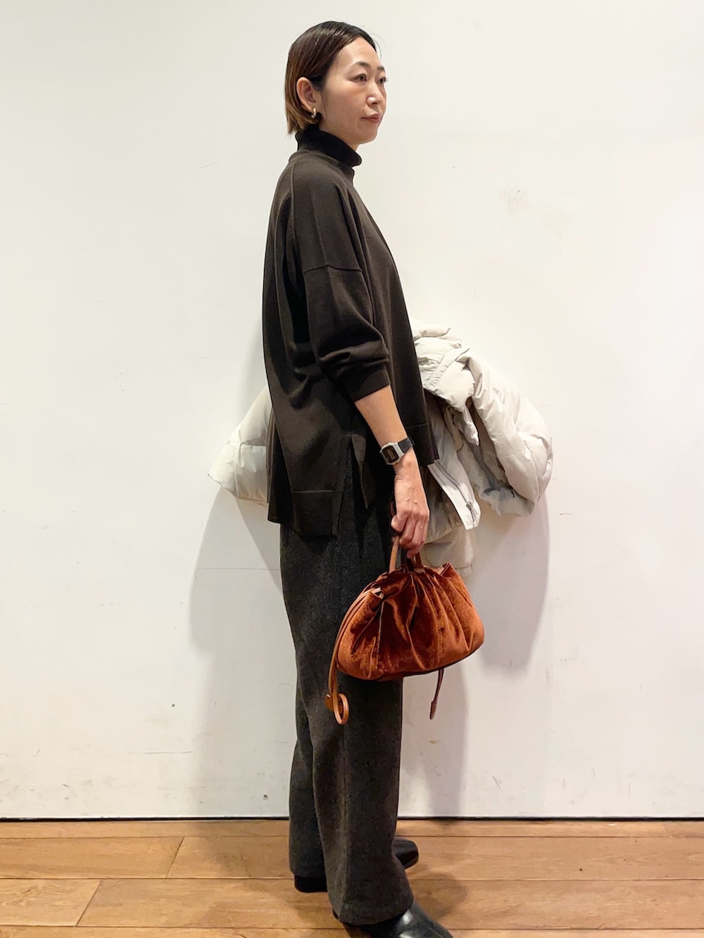 ホワイト系のダウンジャケット/コート、ブラウン系のニット/セーター、ブラック系のブーツを着用したレディースの秋コーディネートの7枚目の写真