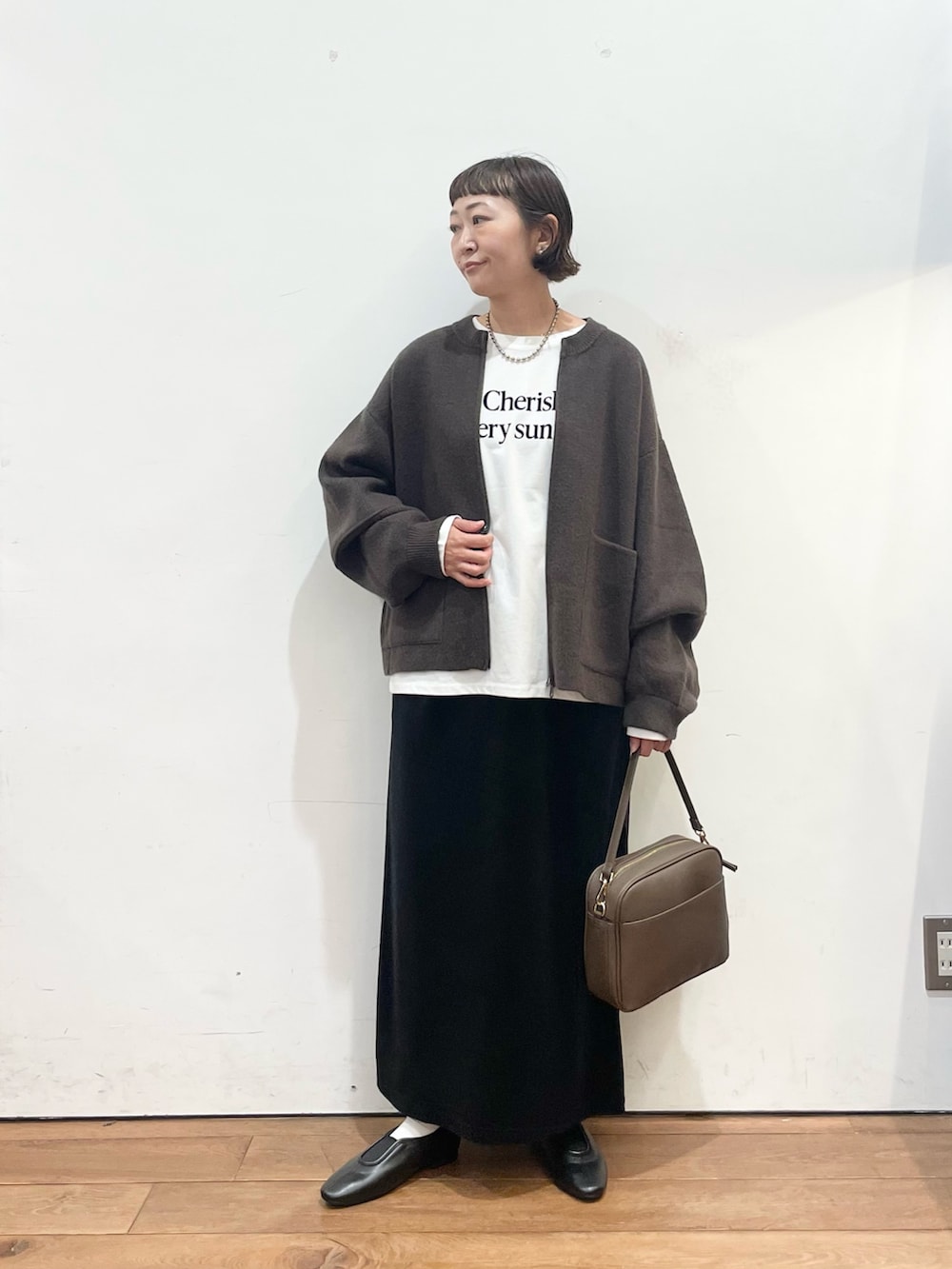 ブラウン系のブルゾン、ホワイト系のTシャツ/カットソー、ブラウン系のショルダーバッグを着用したレディースの秋コーディネートの3枚目の写真