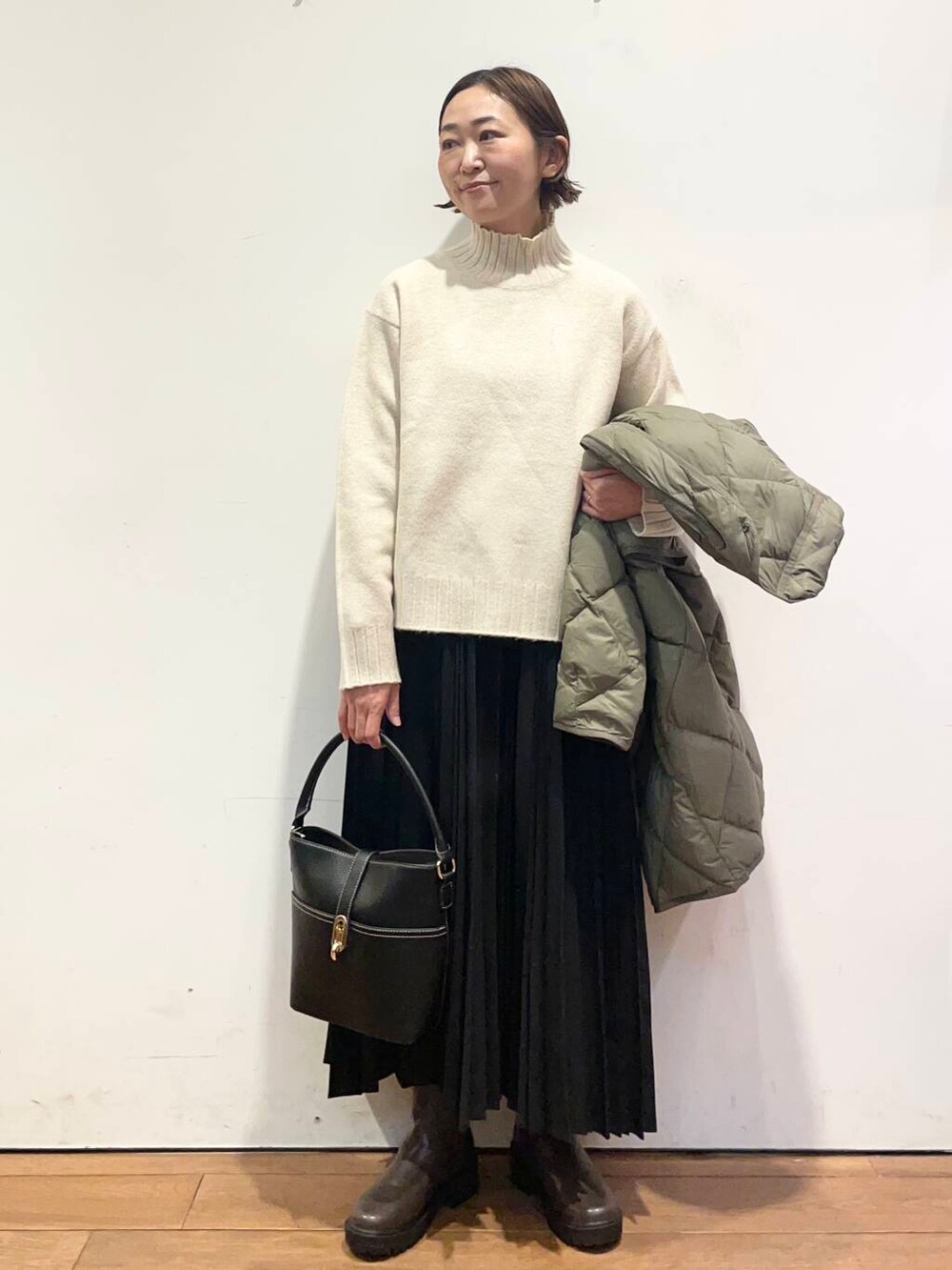 グリーン系のダウンジャケット/コート、ブラック系のハンドバッグ、ブラウン系のブーツを着用したレディースの冬コーディネートの5枚目の写真