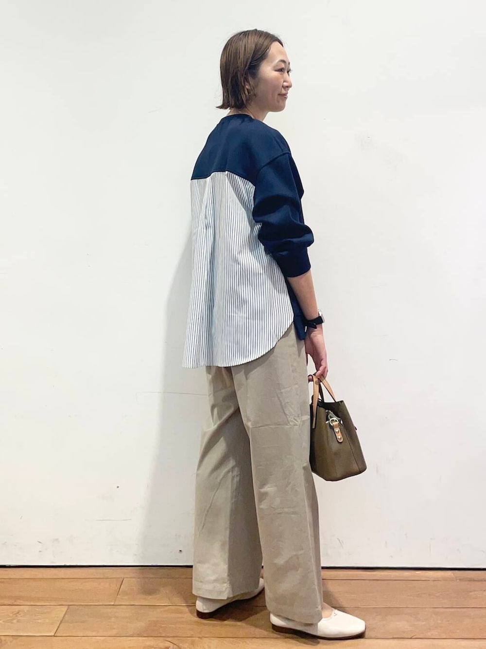 ブラウン系のハンドバッグ、ブルー系のその他トップス、ホワイト系のバレエシューズを着用したレディースの春コーディネートの3枚目の写真